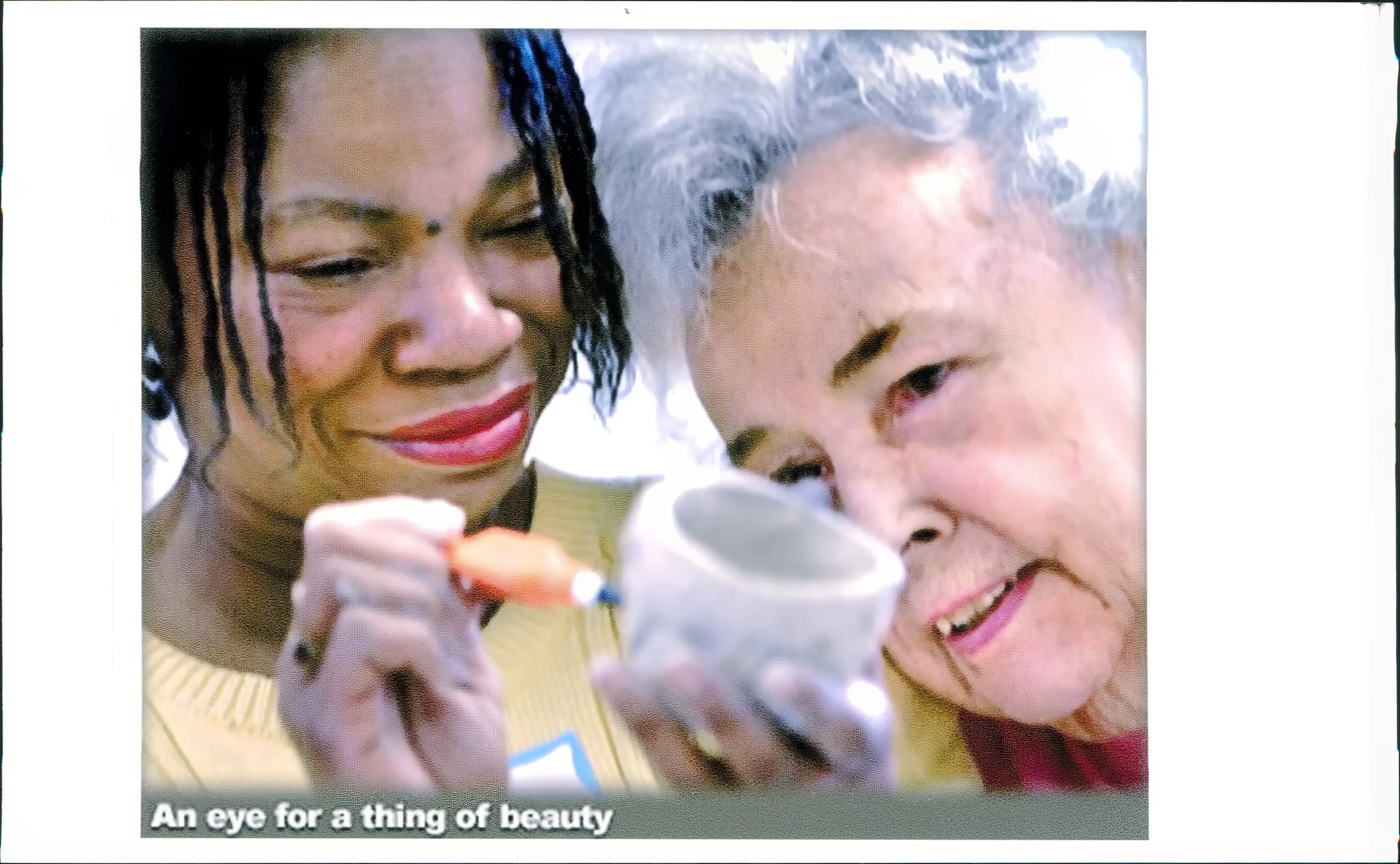 Two women look at a ceramic cup.
