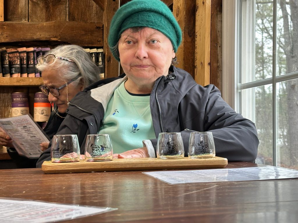 IMG_4284 - IN-SIGHT A woman sits at a table with four small wine glasses in front of her.